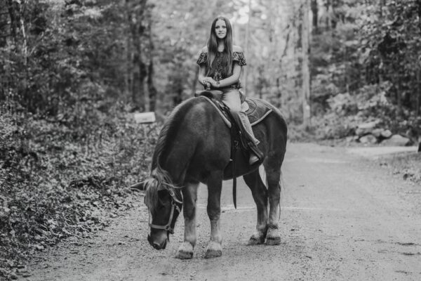 A young woman enjoying a horseback ride in a natural setting