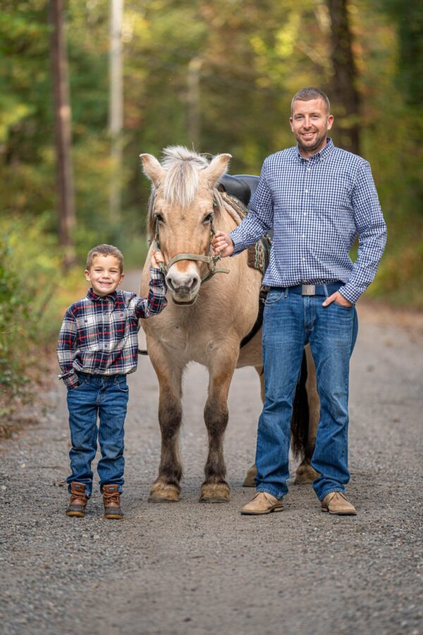 A man and a little boy with a horse between them, sharing a moment together