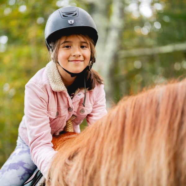 a little girl riding a pony